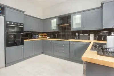 a large kitchen with blue cabinets and appliances at Private room in a spacious home in Moreton
