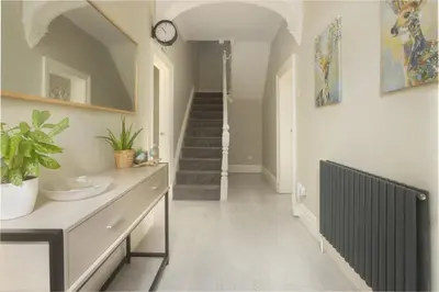 a hallway with a staircase and a clock on the wall at Private room in a spacious home in Moreton