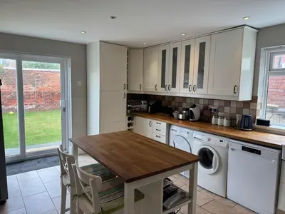 a kitchen with white cabinets and a wooden table at The Links House Lytham St Annes in Lytham St Annes