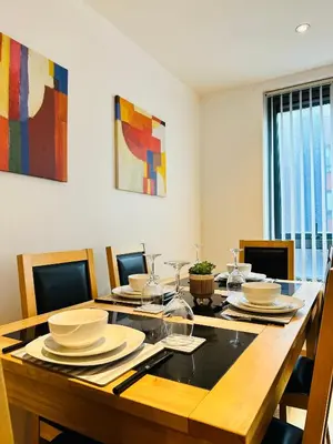 a dining room table with plates and wine glasses at City Centre Free Parking 2 Bedroom Apartment in Liverpool