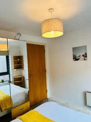 a bedroom with two beds and a light fixture at City Centre Free Parking 2 Bedroom Apartment in Liverpool