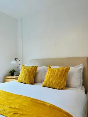 a bed with yellow and white pillows on it at City Centre Free Parking 2 Bedroom Apartment in Liverpool