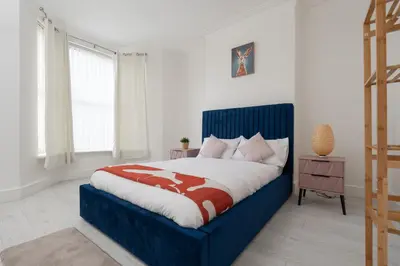 a bedroom with a blue and white bed and a window at Mersey View 4 Bedroom by Liverpoollux Next To Everton Stadium in Liverpool