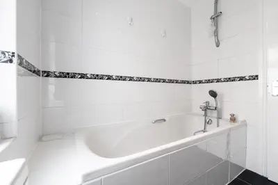a white tub in a bathroom with black and white tiles at Mersey View 4 Bedroom by Liverpoollux Next To Everton Stadium in Liverpool