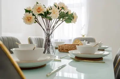 a table with plates and flowers in a vase at Mersey View 4 Bedroom by Liverpoollux Next To Everton Stadium in Liverpool