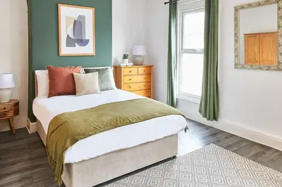 a bedroom with a bed with green walls and a window at Host & Stay - Bishop House in Liverpool