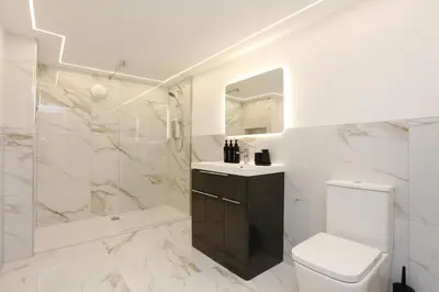 a white bathroom with a toilet and a shower at STAY BY THE SEA Deluxe Apartment in Blackpool