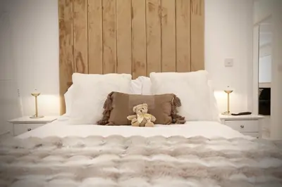 a teddy bear sitting on a bed with pillows at STAY BY THE SEA Deluxe Apartment in Blackpool