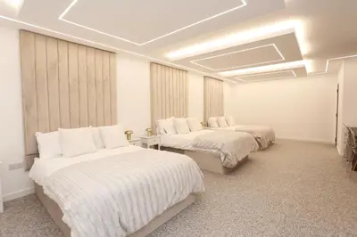 a room with three beds with white sheets and windows at STAY BY THE SEA Deluxe Apartment in Blackpool