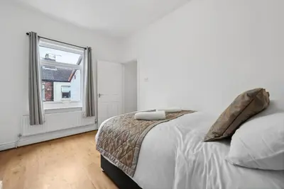 a white bedroom with a bed and a window at Anfield Cozy House in Liverpool