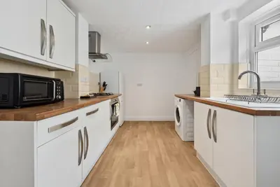 a kitchen with white cabinets and a sink and a microwave at Anfield Cozy House in Liverpool