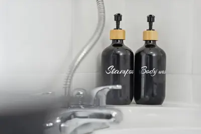 two black glass bottles sitting next to a sink at Anfield Cozy House in Liverpool