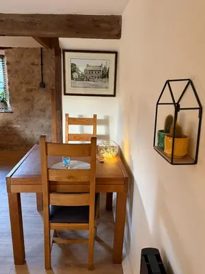 a wooden dining room table with a chair and a picture at The Snug- A beautiful and characterful property connected to a historic Georgian Manor House in Overton