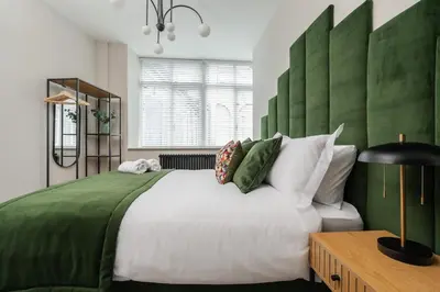 a bedroom with a large bed with a green headboard at Sunnie stays apartment harrington chambers in Liverpool