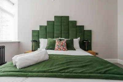a large bed with a green headboard in a bedroom at Sunnie stays apartment harrington chambers in Liverpool