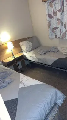 a room with two beds and a desk with a lamp at Bills place in Heysham
