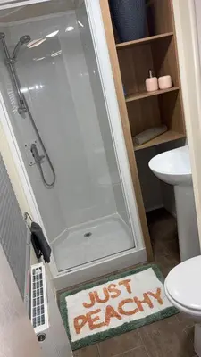 a shower in a bathroom with a toilet and a rug at Bills place in Heysham