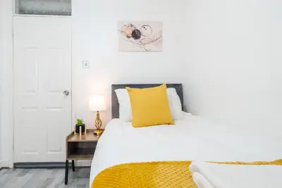 a bedroom with a white bed with a yellow pillow at Newly Renovated 4BR House with lots of amenities in Liverpool