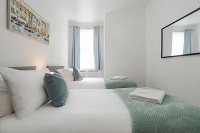 a white bedroom with two beds and a mirror at Newly Renovated 4BR House with lots of amenities in Liverpool