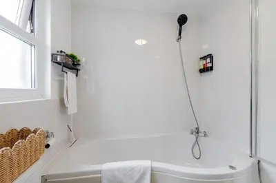 a white bathroom with a shower and a tub at Newly Renovated 4BR House with lots of amenities in Liverpool