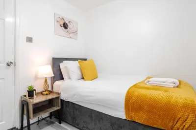 a white bedroom with a bed and a night stand at Newly Renovated 4BR House with lots of amenities in Liverpool