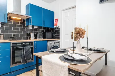 a kitchen with blue cabinets and a wooden table at Newly Renovated 4BR House with lots of amenities in Liverpool