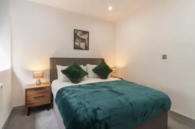 a bedroom with a bed with green sheets and pillows at Cosy & Bright 1 Bedroom Preston Apartment in Preston