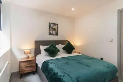 a bedroom with a bed with green sheets and pillows at Cosy & Bright 1 Bedroom Preston Apartment in Preston