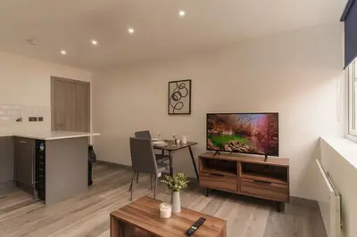 a living room with a table and a tv on the wall at Cosy & Bright 1 Bedroom Preston Apartment in Preston