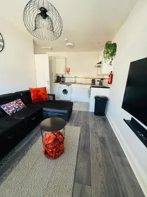 a living room with a black couch and a kitchen at JMC Place - The Duplex in Blackpool
