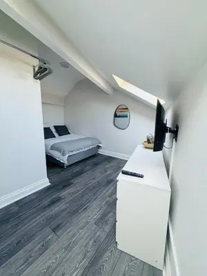 a room with a bed and a dresser with a television at JMC Place - The Duplex in Blackpool