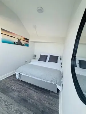 a white bedroom with a bed and a mirror at JMC Place - The Duplex in Blackpool