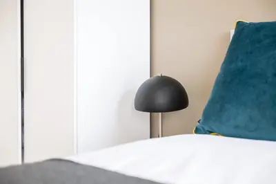 a bed with a black lamp next to a blue pillow at Contemporary 1BED Apartment in Central Liverpool in Liverpool