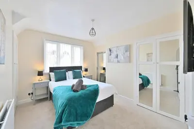 a bedroom with a large bed and a mirror at Sleek and Stylish 3 Bed in Bolton-Garden-Parking in Bradshaw