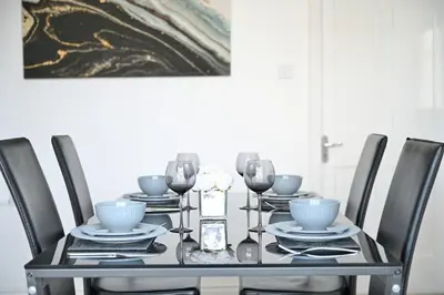 a black dining room table with chairs and a painting at Sleek and Stylish 3 Bed in Bolton-Garden-Parking in Bradshaw