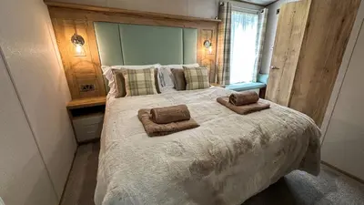 a bedroom with a large bed with two towels on it at Hobbit - House Of The Owl - Luxury Lodge with Pool in Longridge