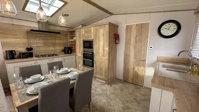 a kitchen with a table with chairs and a clock on the wall at Hobbit - House Of The Owl - Luxury Lodge with Pool in Longridge