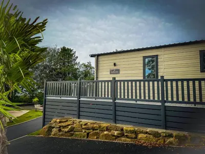 a fence in front of a house with a building at Hobbit - House Of The Owl - Luxury Lodge with Pool in Longridge