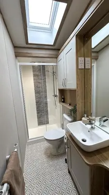 a bathroom with a sink and a toilet and a skylight at Hobbit - House Of The Owl - Luxury Lodge with Pool in Longridge
