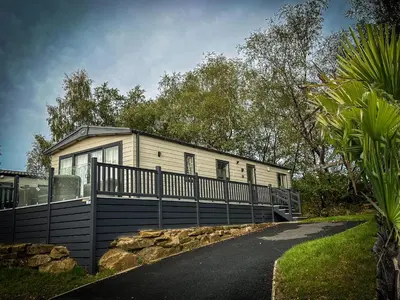 a house with a black fence in front of it at Hobbit - House Of The Owl - Luxury Lodge with Pool in Longridge