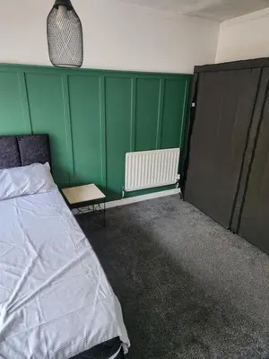 a bedroom with a bed and a green wall at Okwute,s House in Skelmersdale