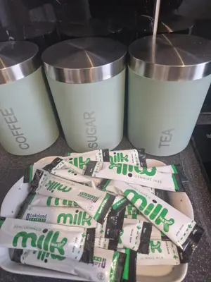 a pile of milk bags and two cups on a counter at Leyland Town Centre Quiet Hub 2 bedroom 4 beds superfast WIFI free parking close to station and High Street in Leyland