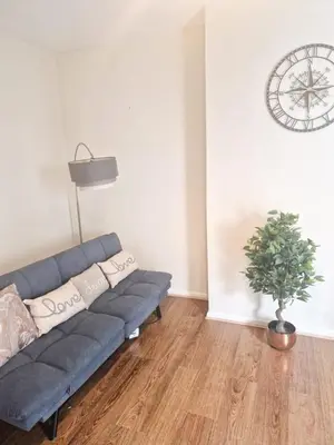 a blue couch in a living room with a clock on the wall at Leyland Town Centre Quiet Hub 2 bedroom 4 beds superfast WIFI free parking close to station and High Street in Leyland