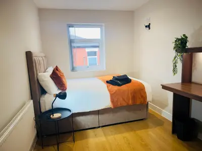 a bedroom with a bed with an orange blanket and a window at Lovat House - Large 6-Bedroom Property in Preston