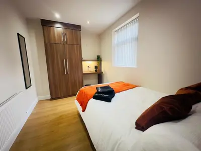 a bedroom with a bed and a wooden cabinet at Lovat House - Large 6-Bedroom Property in Preston