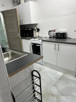 a kitchen with white cabinets and a sink and a counter at KD Homes in Horwich