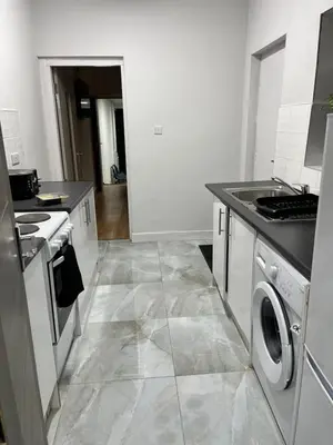 a kitchen with a washer and dryer on a tile floor at KD Homes in Horwich