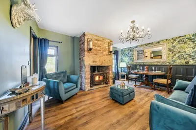 a living room with a fireplace and blue furniture at The Stables in Poulton le Fylde