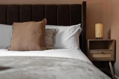 a bed with a brown headboard and white pillows at City Centre Retreat 2BR 2BA Parking Included in Liverpool