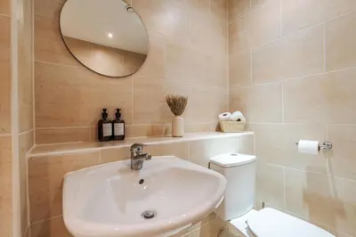 a bathroom with a sink and a toilet and a mirror at City Centre Retreat 2BR 2BA Parking Included in Liverpool